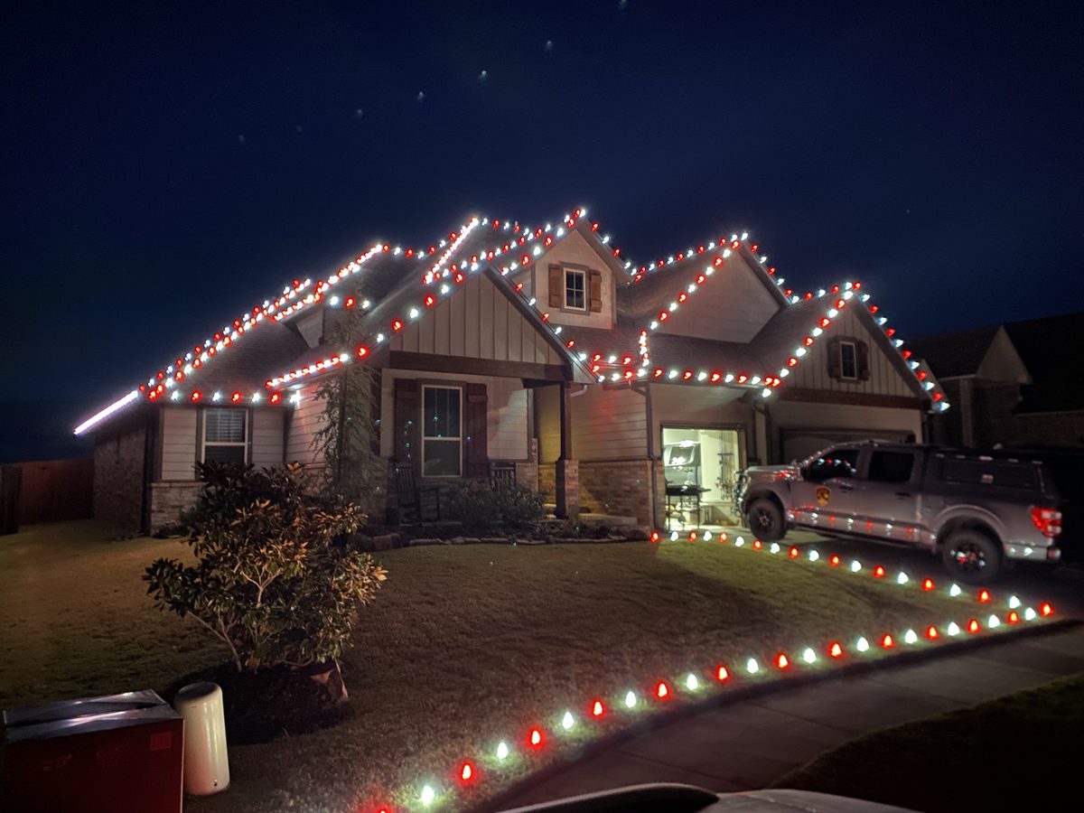 Edmond home with red and white Christmas lights installed along the roofline and driveway by Brandon Seasonal Solutions