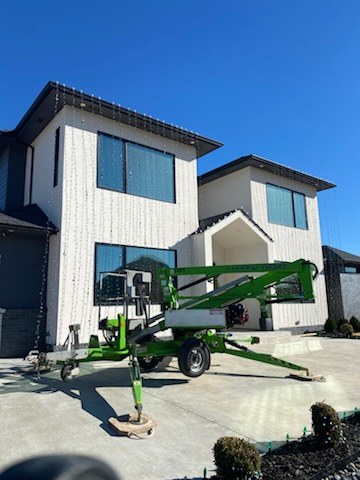 Boom lift parked at a white two story home during a light install