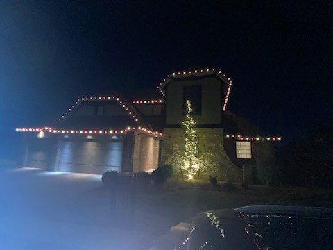 Home lit along the roofline at night with the driveway washed in light