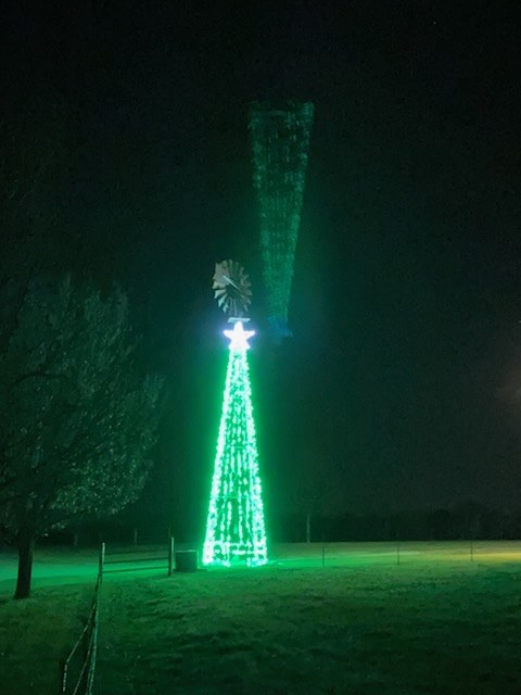 Tall tower wrapped top to bottom in green lights on an open property