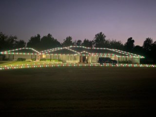 Long low home lined end to end in warm white lights at dusk