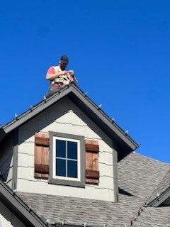 Installer on a steep roof clipping lights along the edge