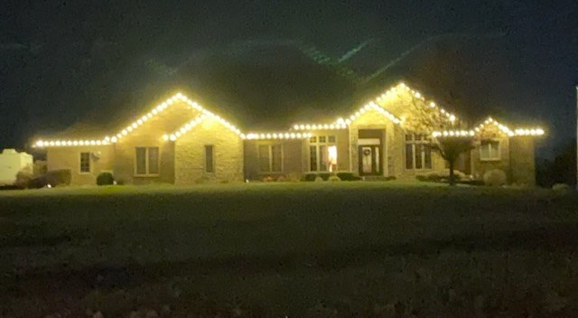 Wide roofline lit in warm white lights across the whole front of the house