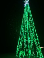 Large mega tree built from green lights standing in an open yard