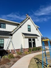 Crew setting a ladder against a white home to start a light install
